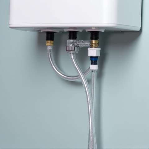 Water descaling pump setup for tankless water heater maintenance. A professional descaling pump setup connected to a tankless water heater, illustrating the effective method used to circulate descaling solution and prevent mineral buildup.